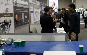 robotic hand with ball near atable with cup and people at CES